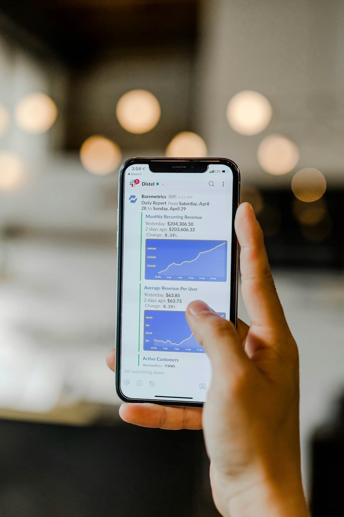 A hand holding a phone showing an app's analytics chart
