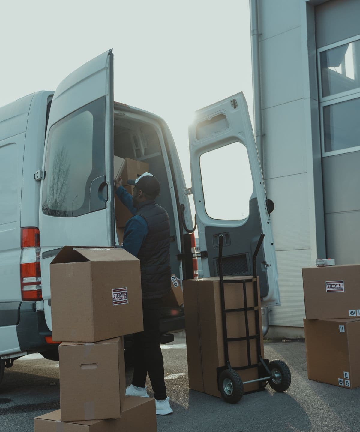 A worker loading boxes into a van outside a depot