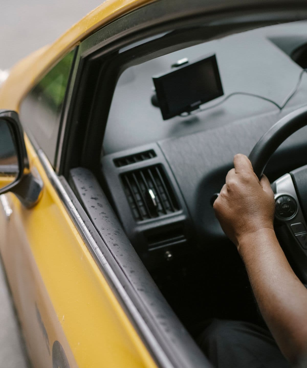 A driver at the wheel of a taxi with a satnav mounted on the dashboard