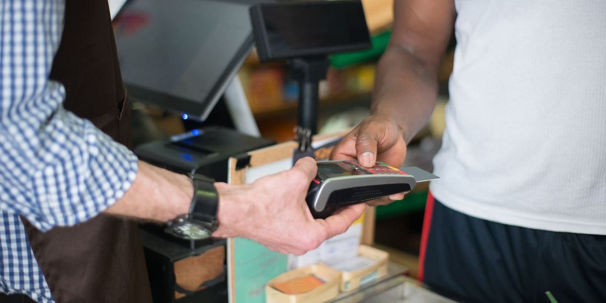 A customer paying at a shop counter while the assistant scans an item
