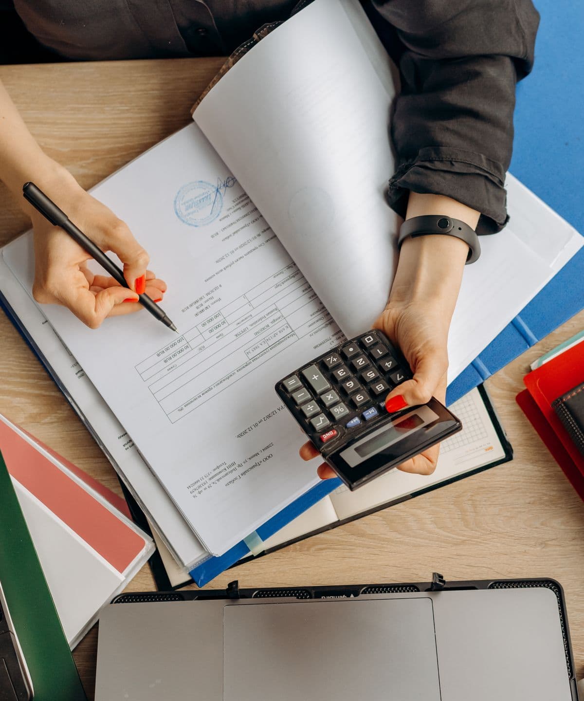An accountant working through documents with a calculator at a desk