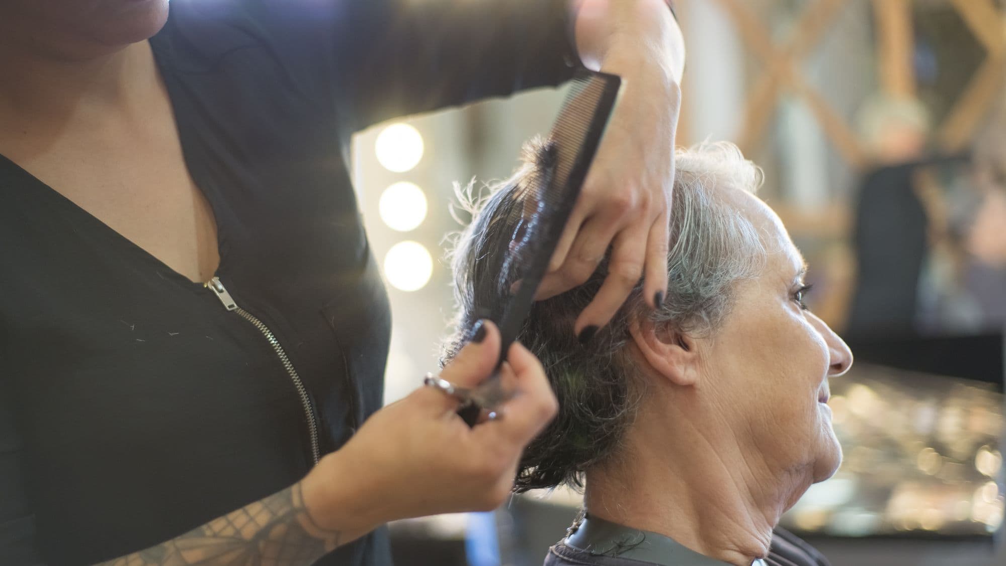 A hairdresser working with a client in a warm, busy salon