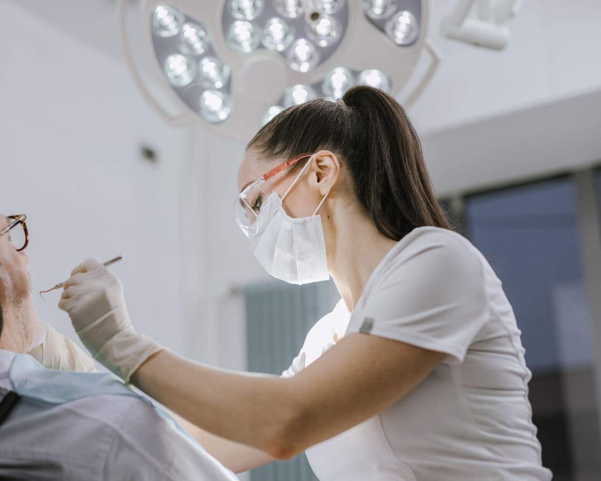 A dentist working on a patient under the surgery light