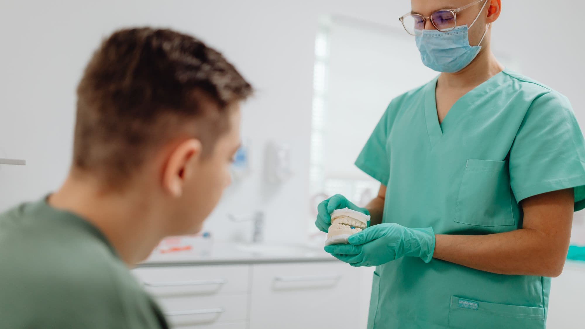 A dentist explaining a treatment plan to a patient across a desk