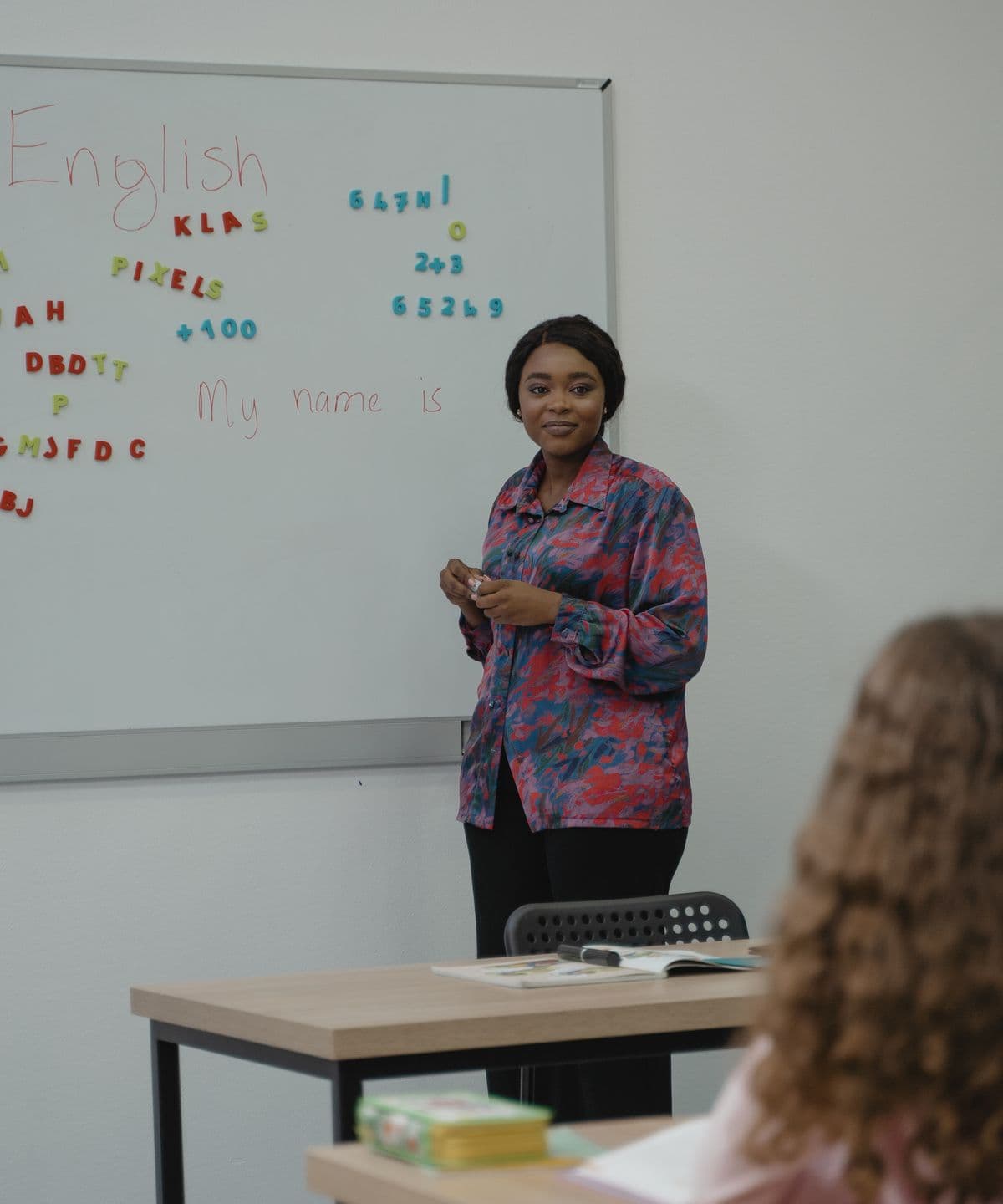 A teacher explaining a lesson at a whiteboard to a small class