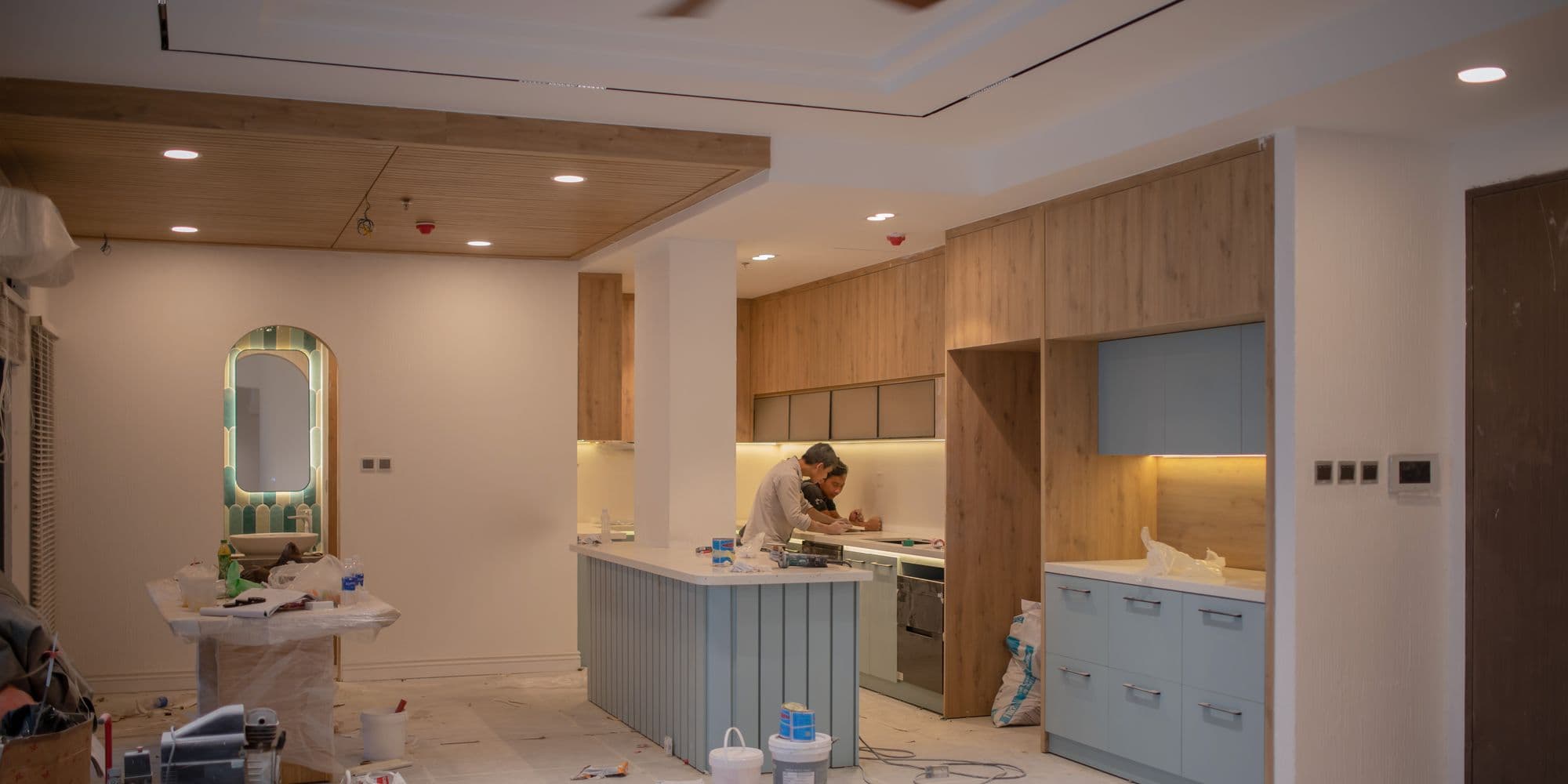 A fitter working on a part finished kitchen with tools and materials still on the floor