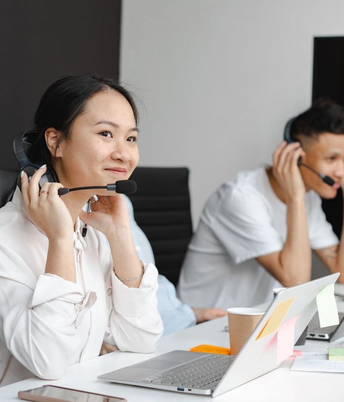 Two colleagues at their desks wearing headsets, working in daylight