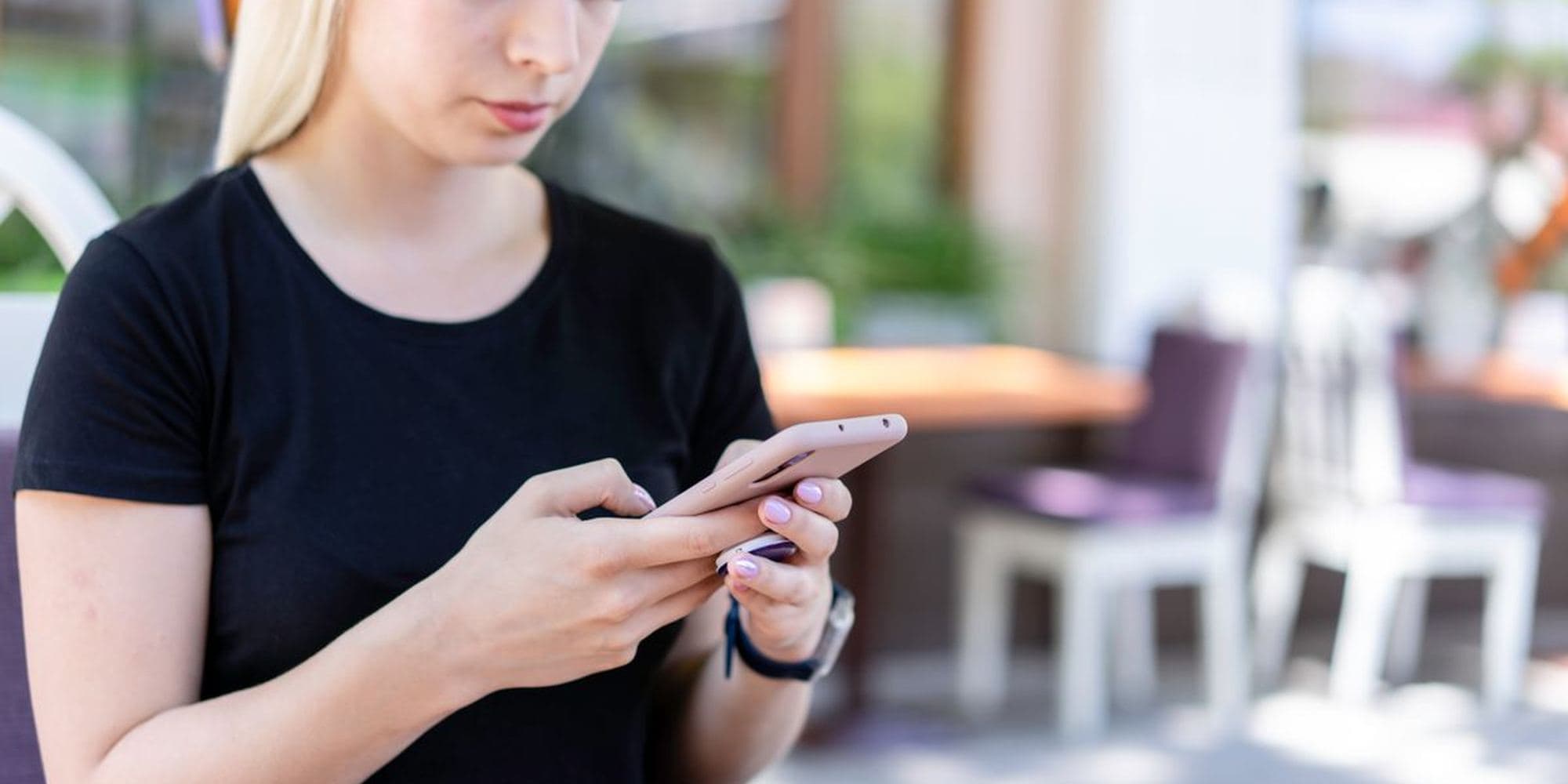 A woman looking at her phone outside a café in daylight