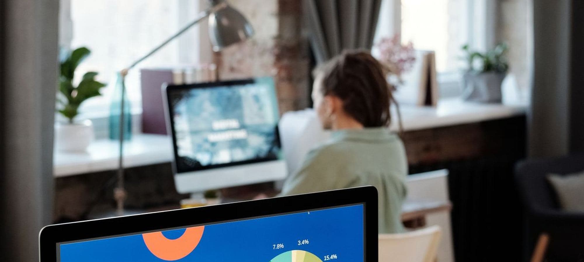 A person at a desk with a breakdown of ad spend on screen