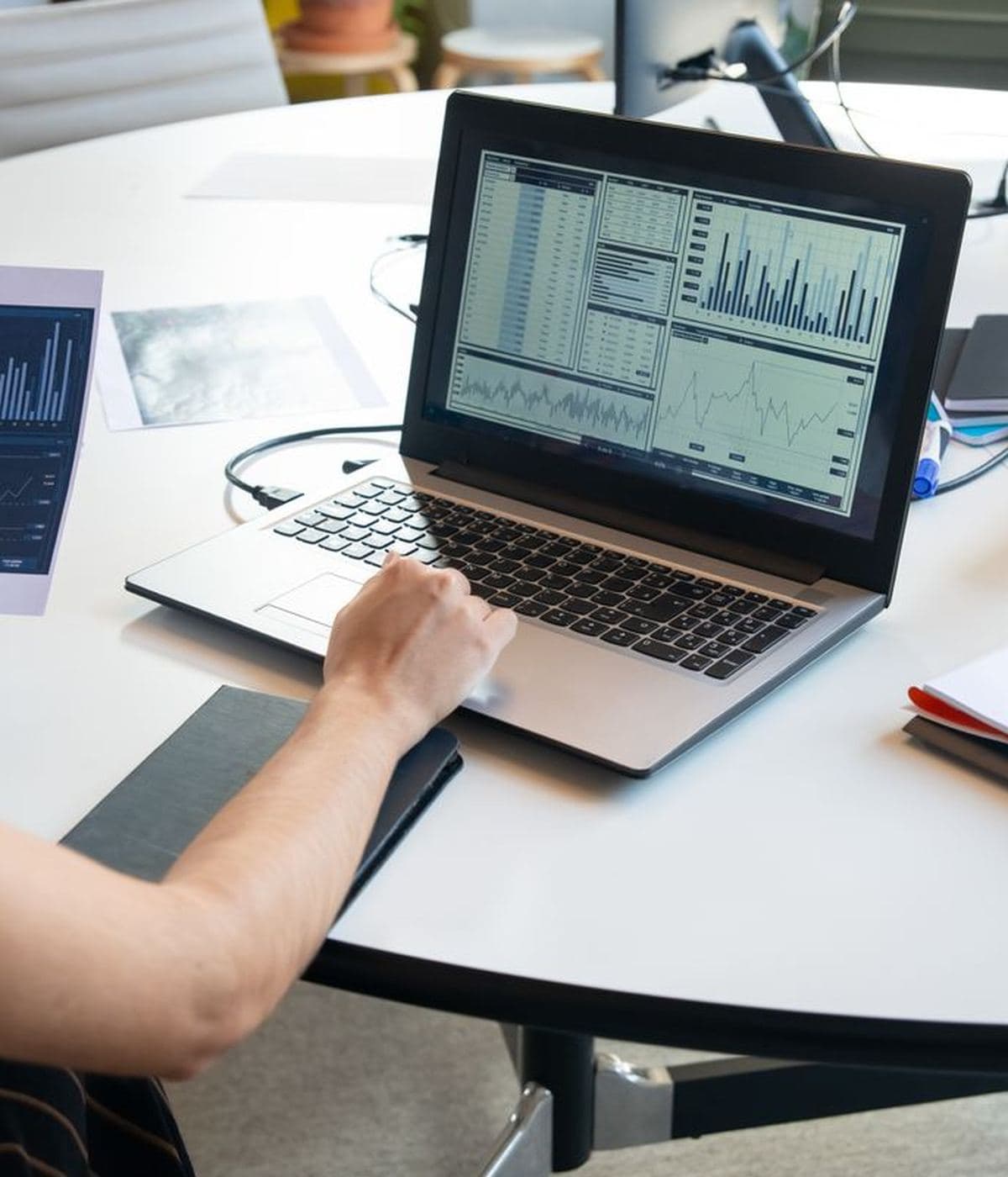 Someone working at a laptop showing charts, with a second screen beside it