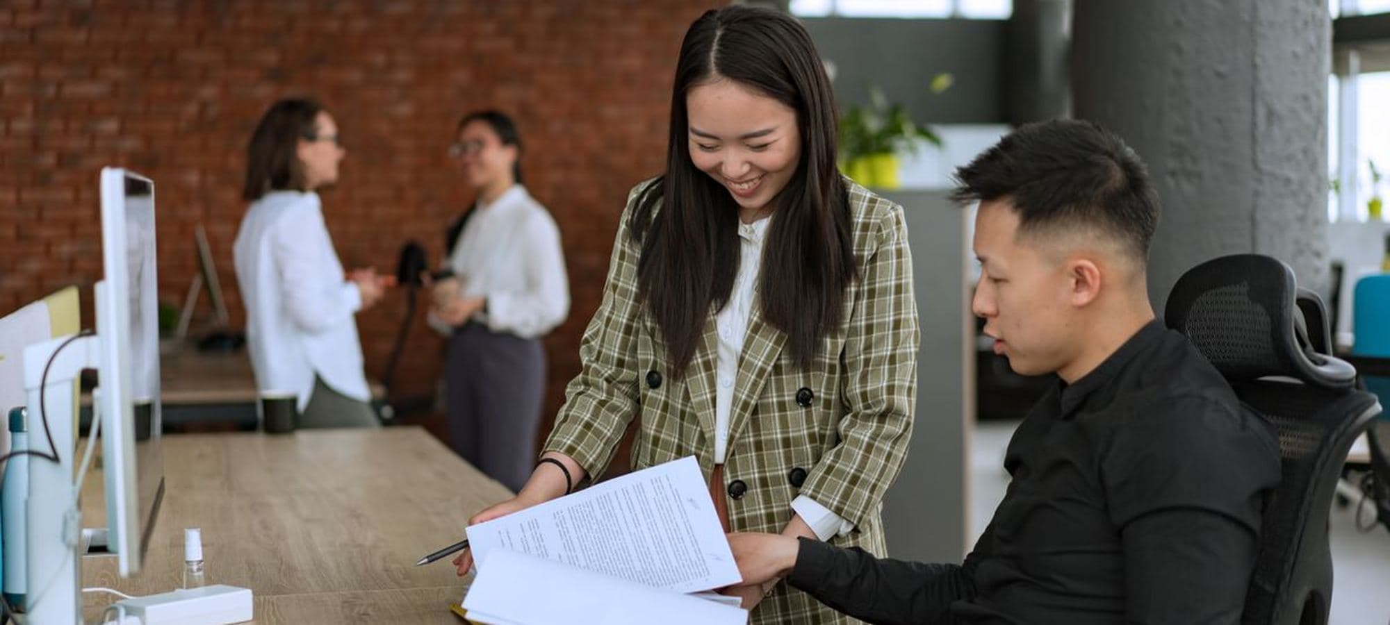 Two colleagues going through a printed report together at a desk